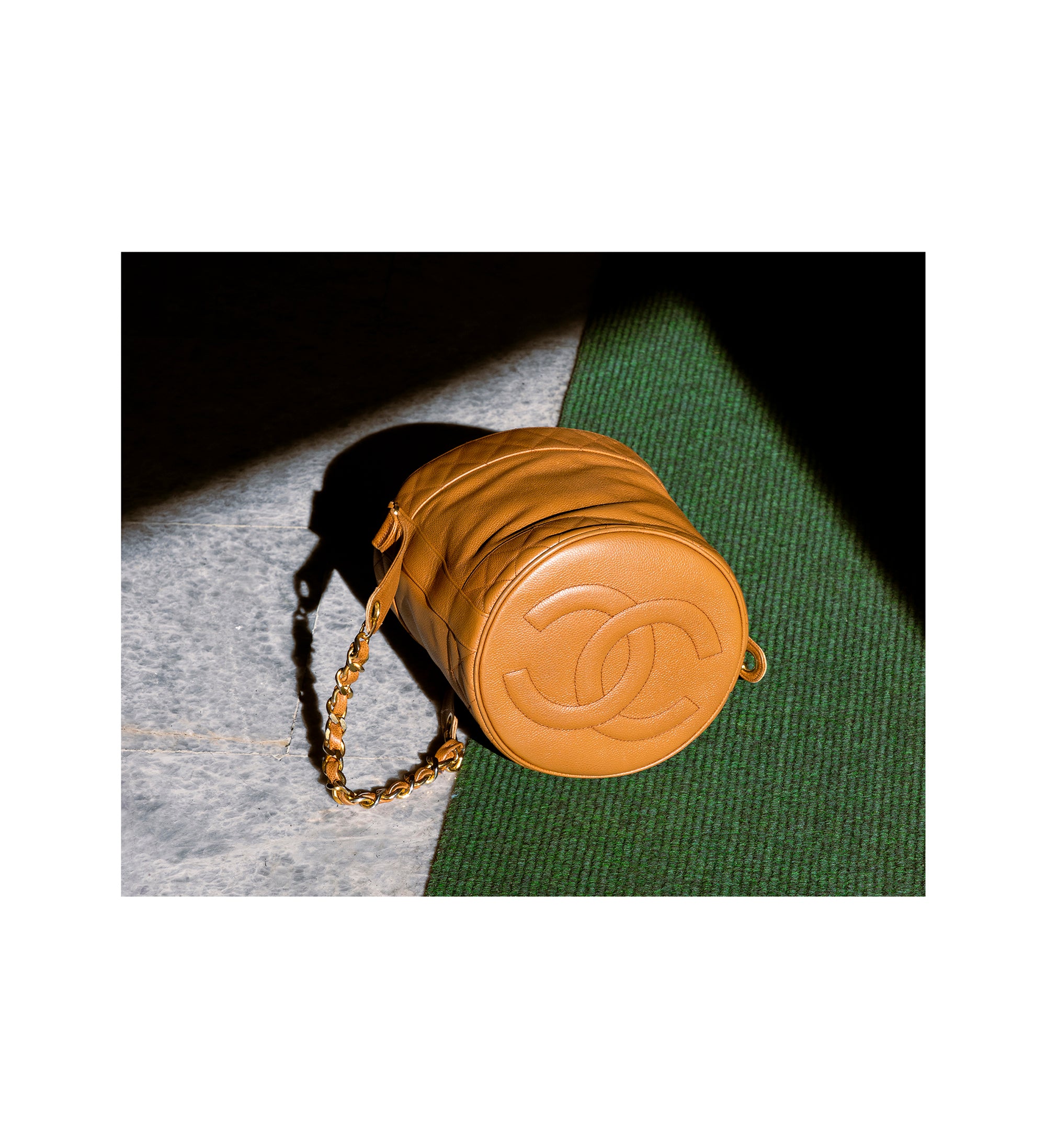 Stylish tan Chanel bag with a round design, resting on a textured surface - HerAge