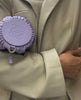 Lilac Loewe round leather bag worn with a pale green tailored look