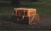 Two vintage Louis Vuitton monogram suitcases stacked on the ground in a wooded outdoor setting.